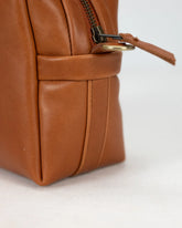 Close-up of a brown leather bag with a zipper on a white background
