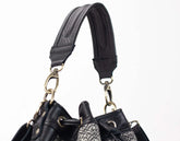 Close-up of a black leather handbag with a strap on a white background