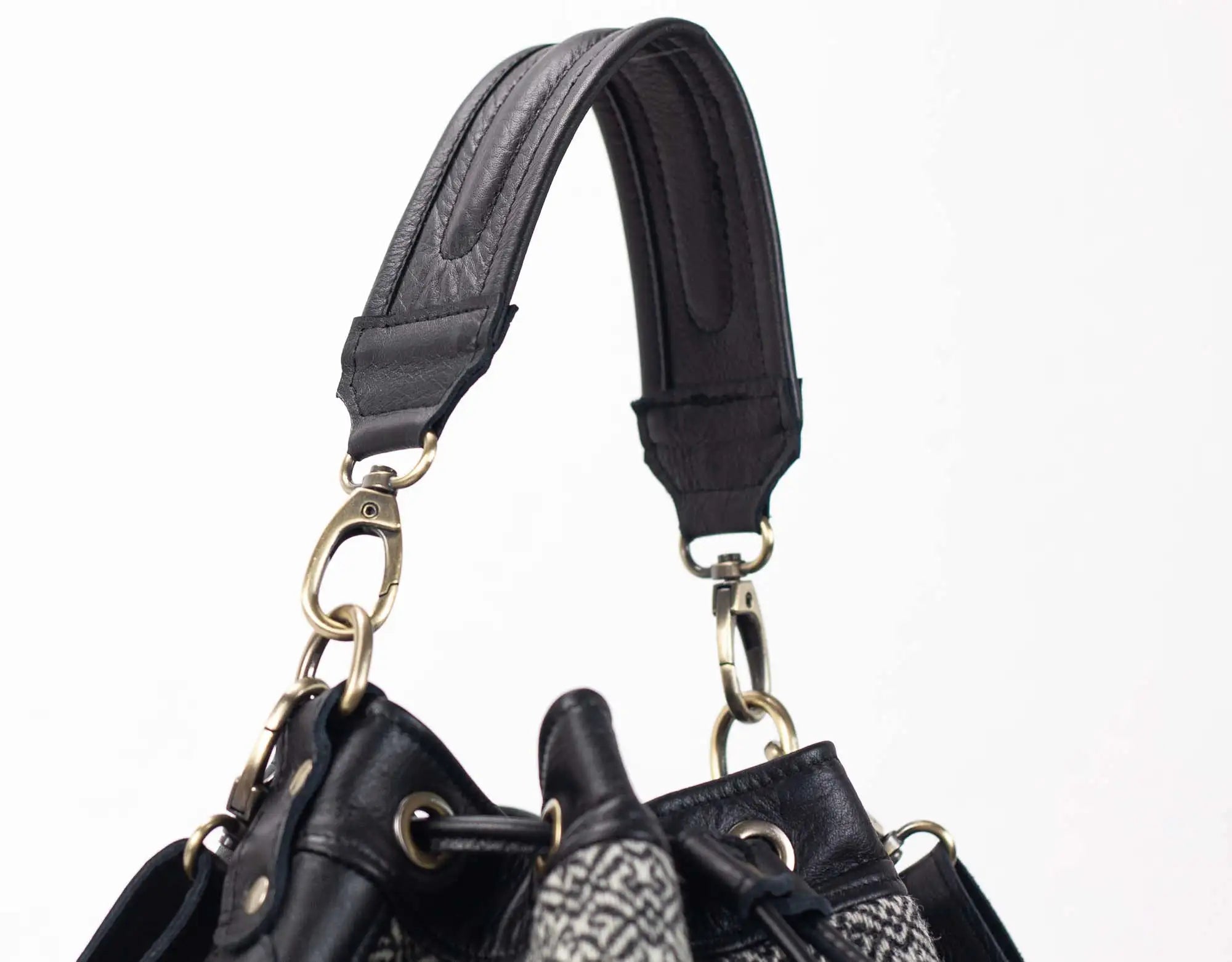Close-up of a black leather handbag with a strap on a white background