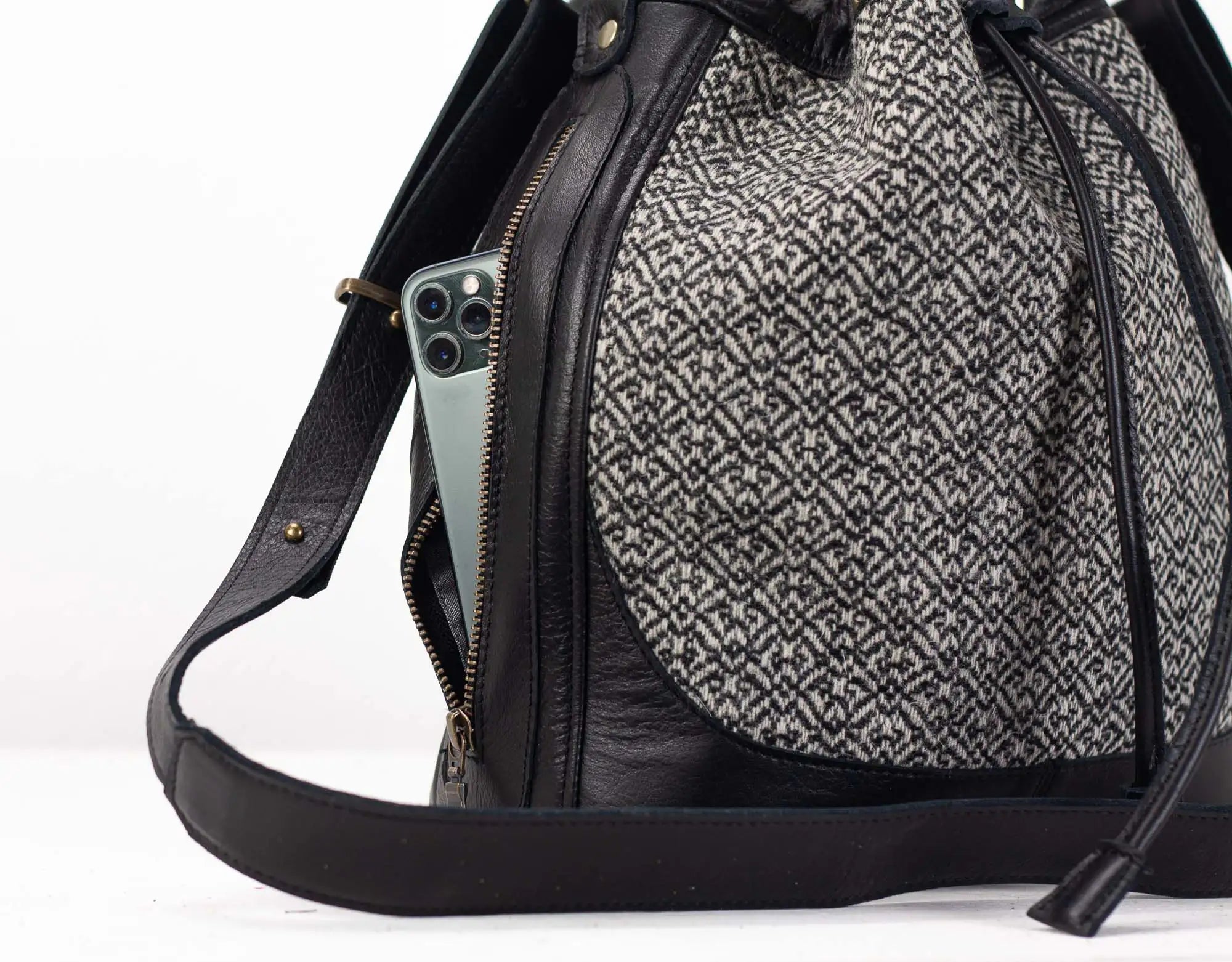 Black and gray patterned backpack with a phone inside on a white background