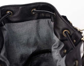 Close-up of a black leather bag with drawstring and metal eyelets on a white background