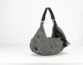 Gray textured handbag with a black strap on a white background