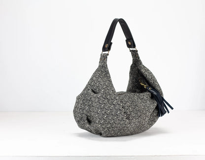 Gray textured handbag with a black strap on a white background