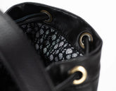Close-up of a black leather drawstring bag with patterned interior.