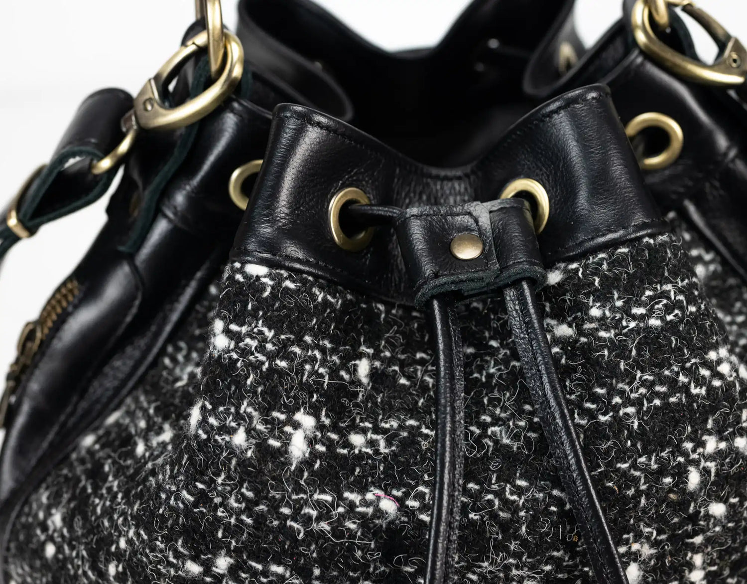 Black and white tweed handbag with gold accents on a white background