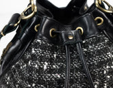 Black and white tweed handbag with gold accents on a white background