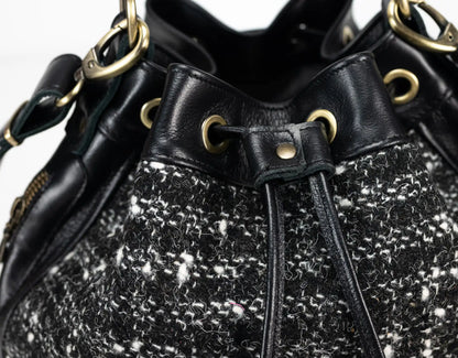 Black and white tweed handbag with gold accents on a white background