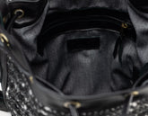 Close-up of a black handbag with studded details on a dark background