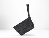 Black textured clutch bag on a white background