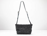 Black textured handbag with a strap on a white background