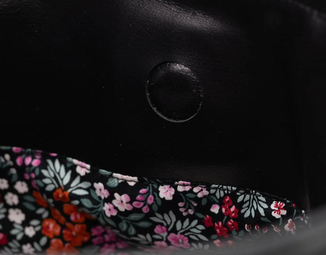 Close-up of a black leather product with floral fabric trim