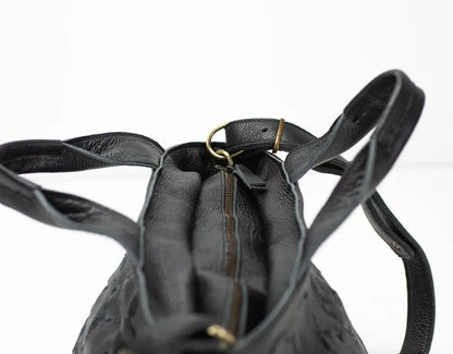 Black leather backpack with a gold zipper on a white background