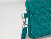 Teal woven handbag with a strap on a white background