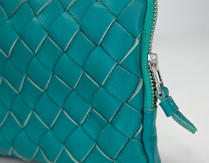 Close-up of a teal woven leather handbag with a zipper.