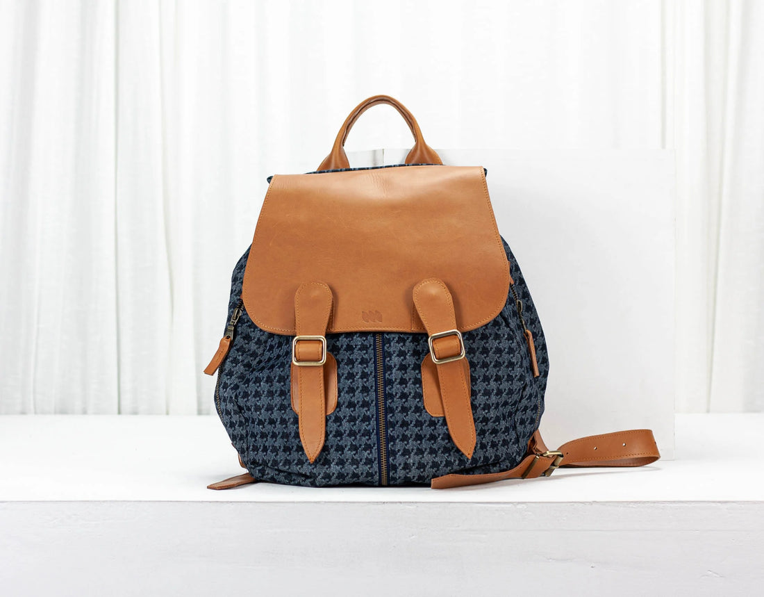 Blue patterned backpack with brown leather accents on a white background