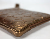 Bronze-colored leather clutch with embossed pattern on a white background