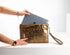 Person holding a gold clutch with a laptop inside on a white background
