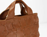 Brown leather handbag with textured pattern on a white background
