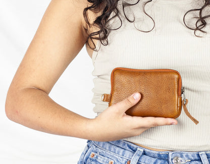 Person holding a brown leather wallet against a neutral background