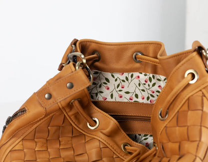 Brown leather handbag with floral interior lining on a white background