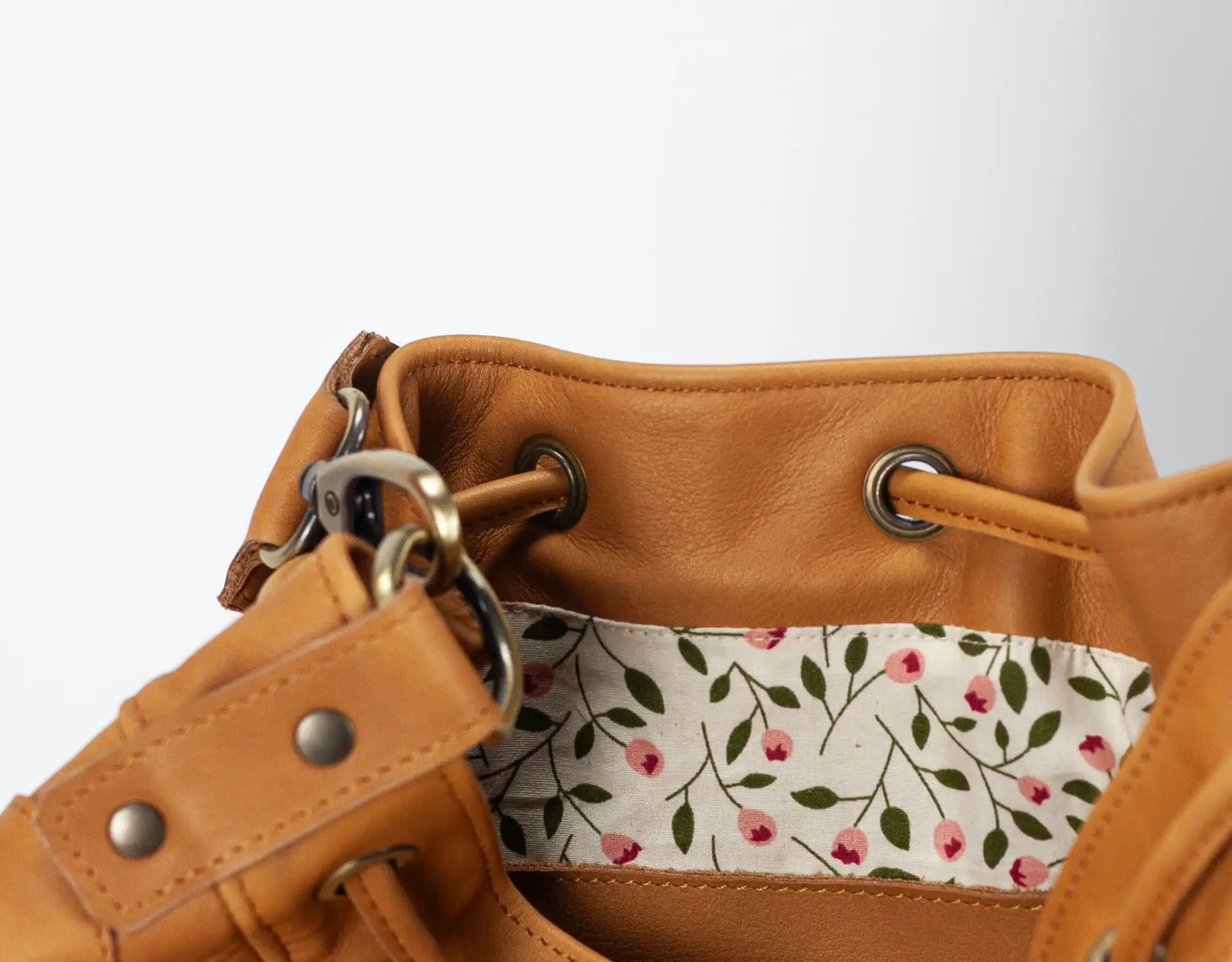 Brown leather bag with floral patterned interior pocket on a white background