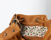 Brown leather bag with floral patterned interior pocket on a white background