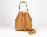 Tan leather bucket bag with a strap on a white background