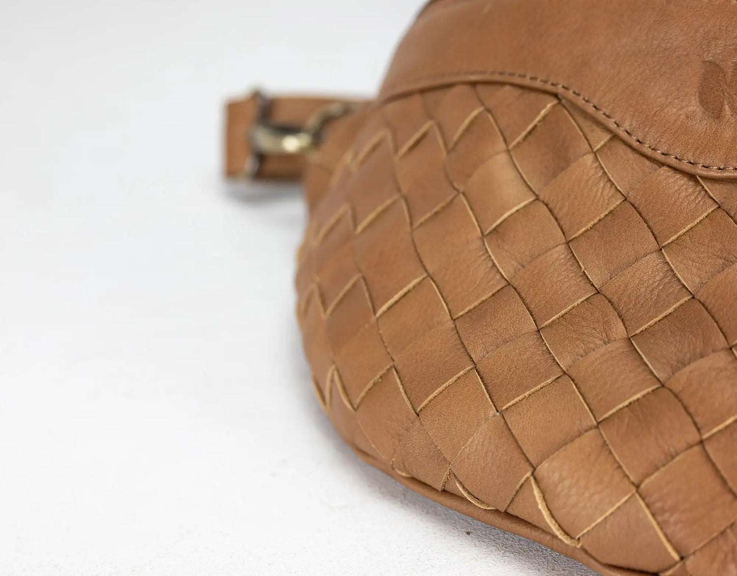 Close-up of a brown woven leather bag on a white background