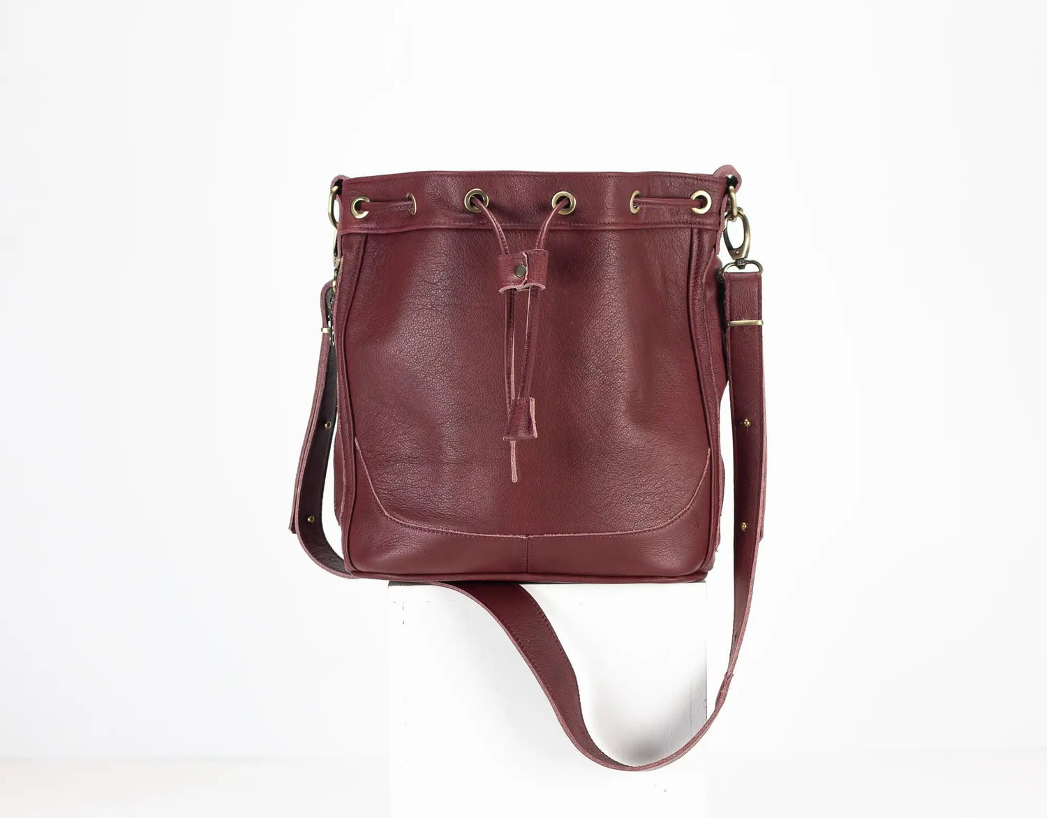 Burgundy leather handbag with a drawstring on a white background