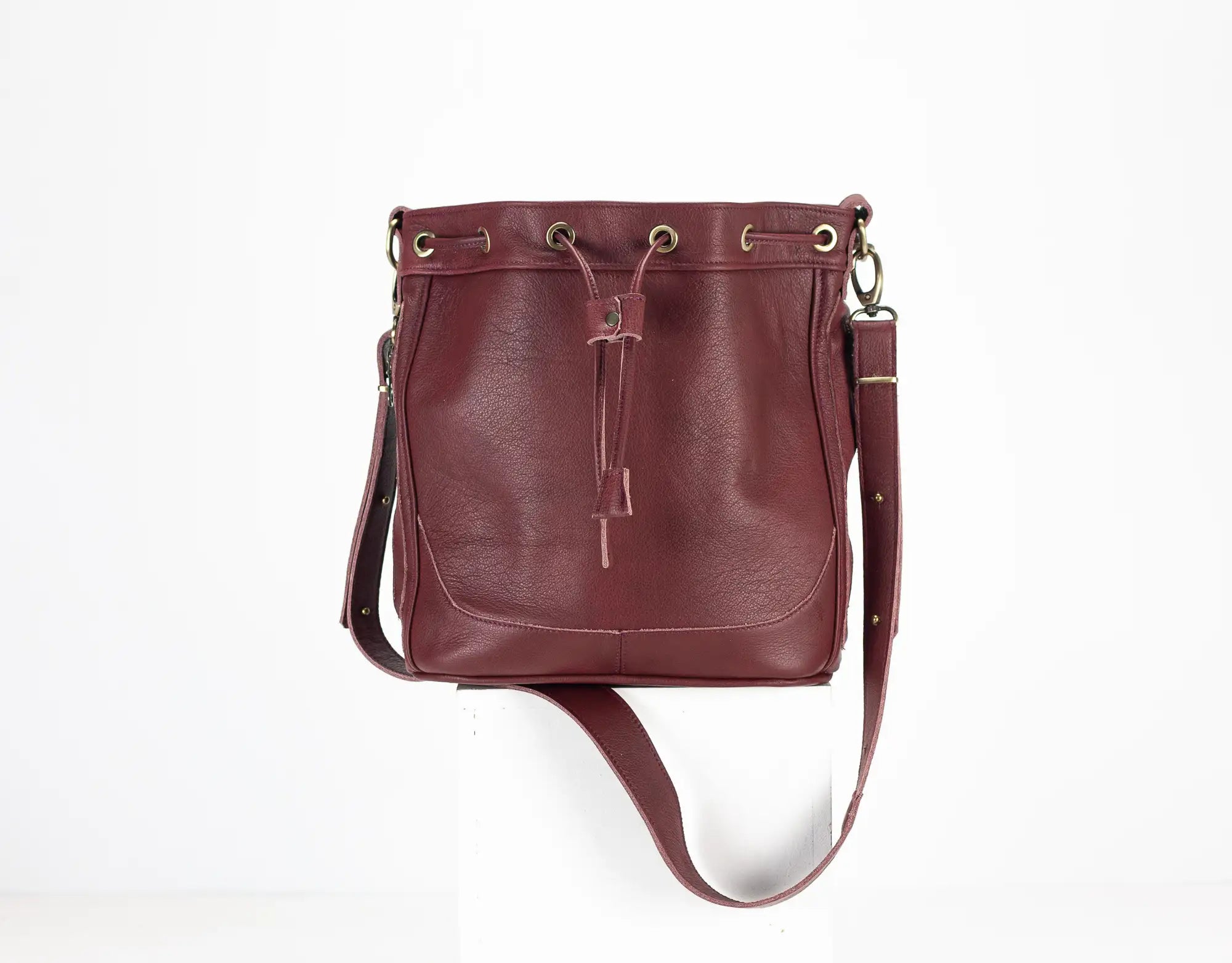Burgundy leather handbag with a drawstring on a white background