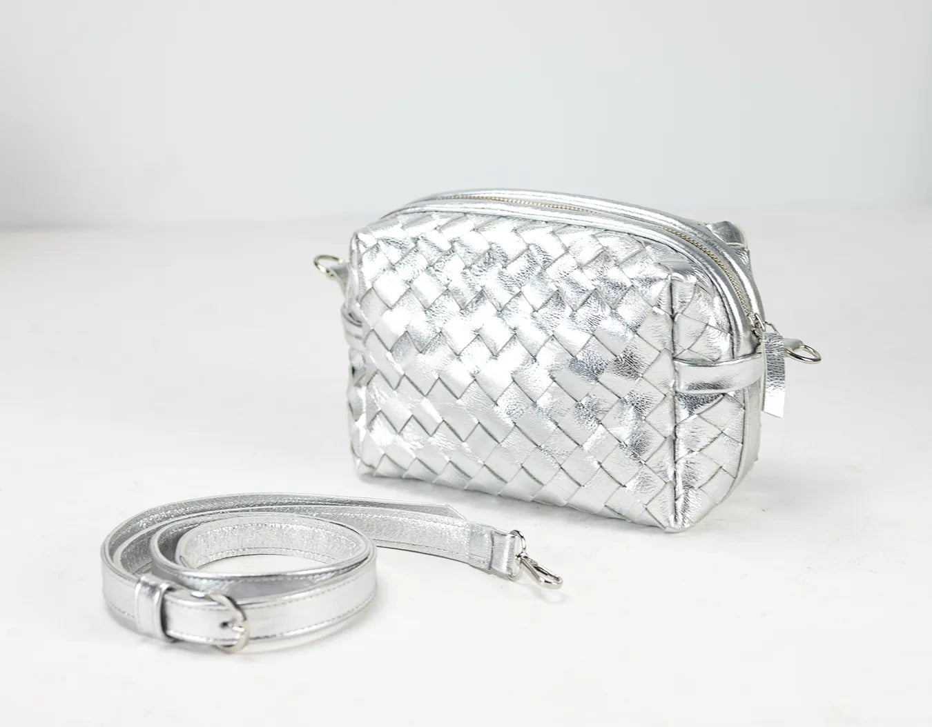 Silver woven handbag with a strap on a white background
