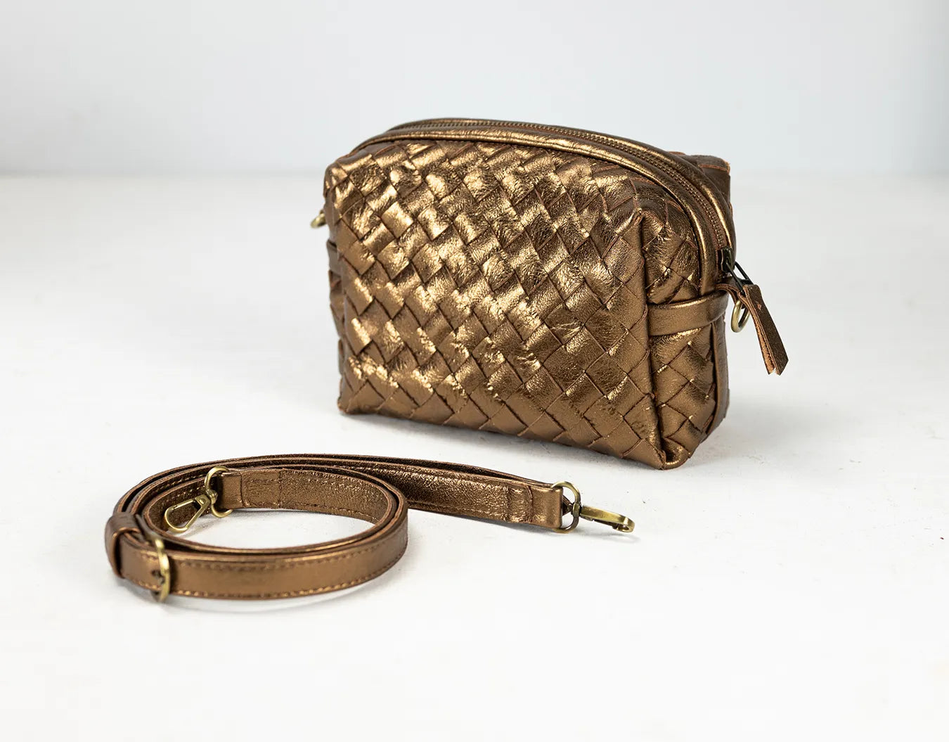 Gold woven handbag with a matching strap on a white background