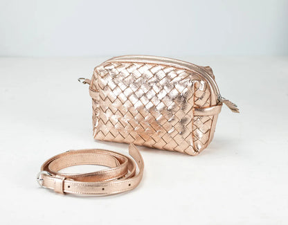 Rose gold woven handbag and matching belt on a light gray background
