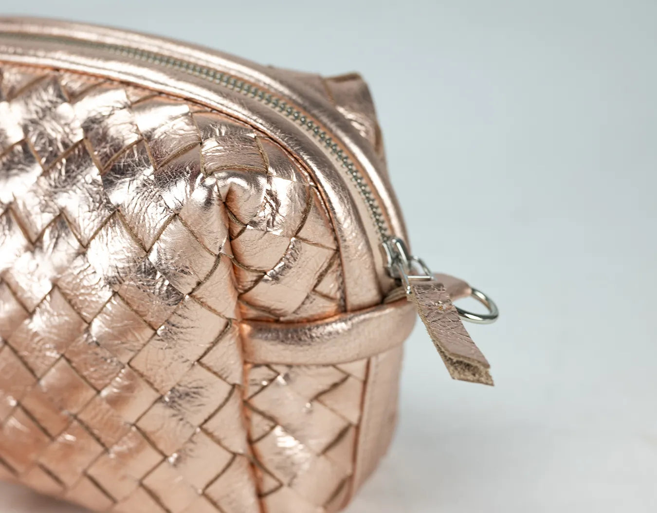Rose gold quilted handbag on a light gray background