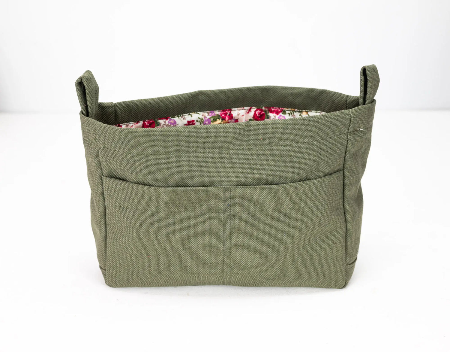 Green fabric basket with floral lining on a white background