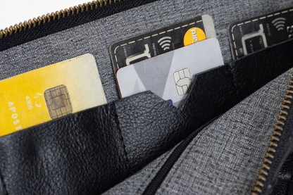 Black woven leather handbag with a zipper open, revealing credit cards inside.