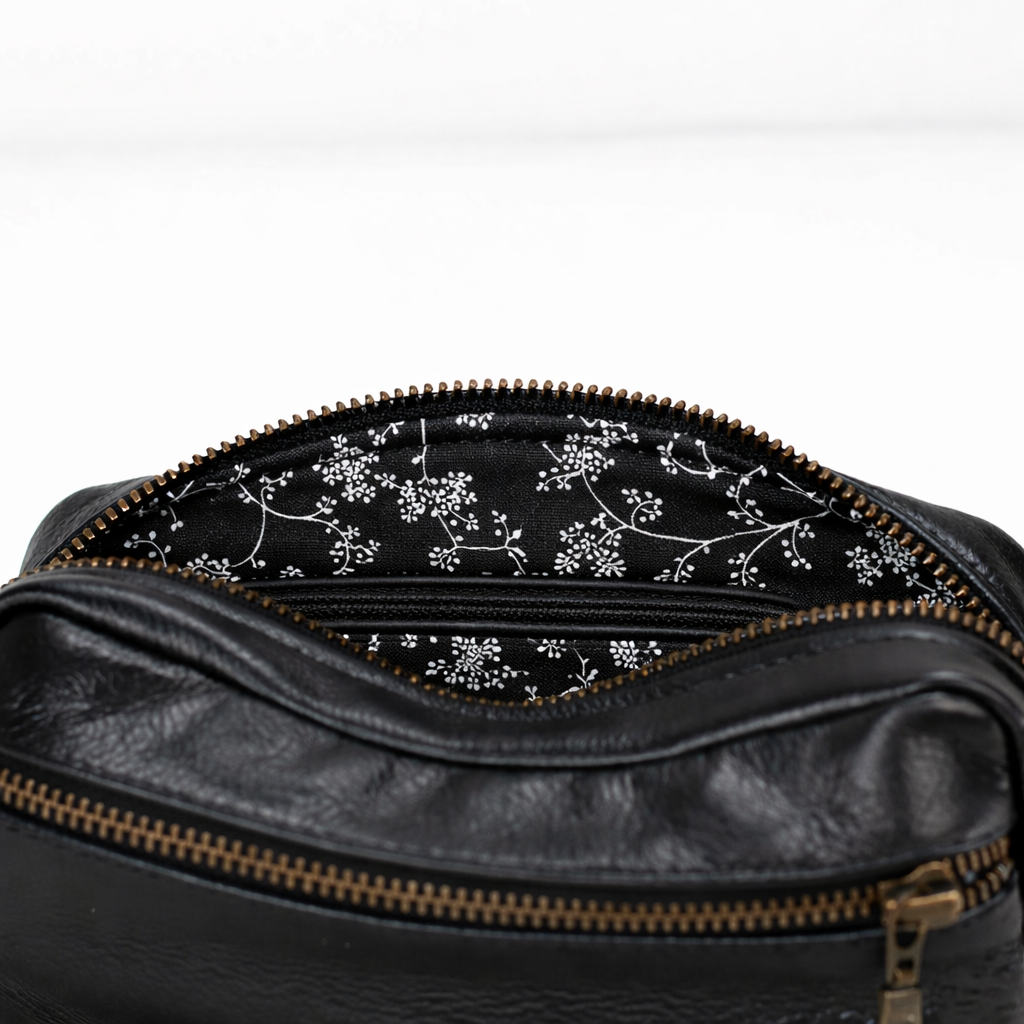Black leather bag with floral patterned interior on a white background