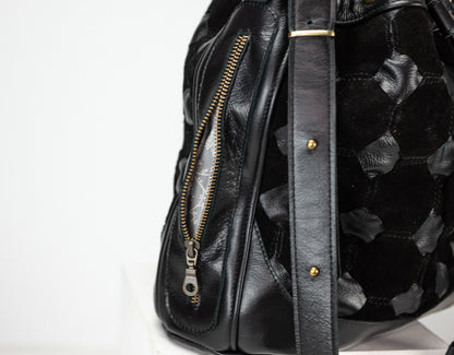 Black leather bag with floral pattern on a white background