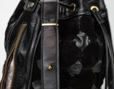 Close-up of a black leather bag with gold hardware on a white background