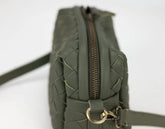 Green quilted handbag with a gold zipper on a white background