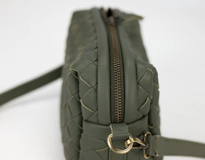 Green quilted handbag with a gold zipper on a white background