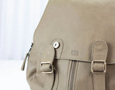 Close-up of a beige backpack with a visible brand logo on a white background
