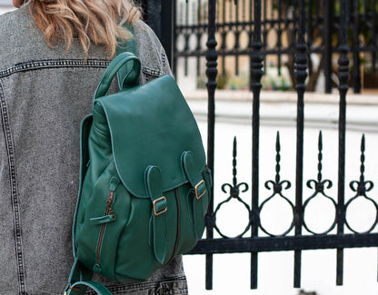 Green backpack worn by a person with a black metal fence in the background