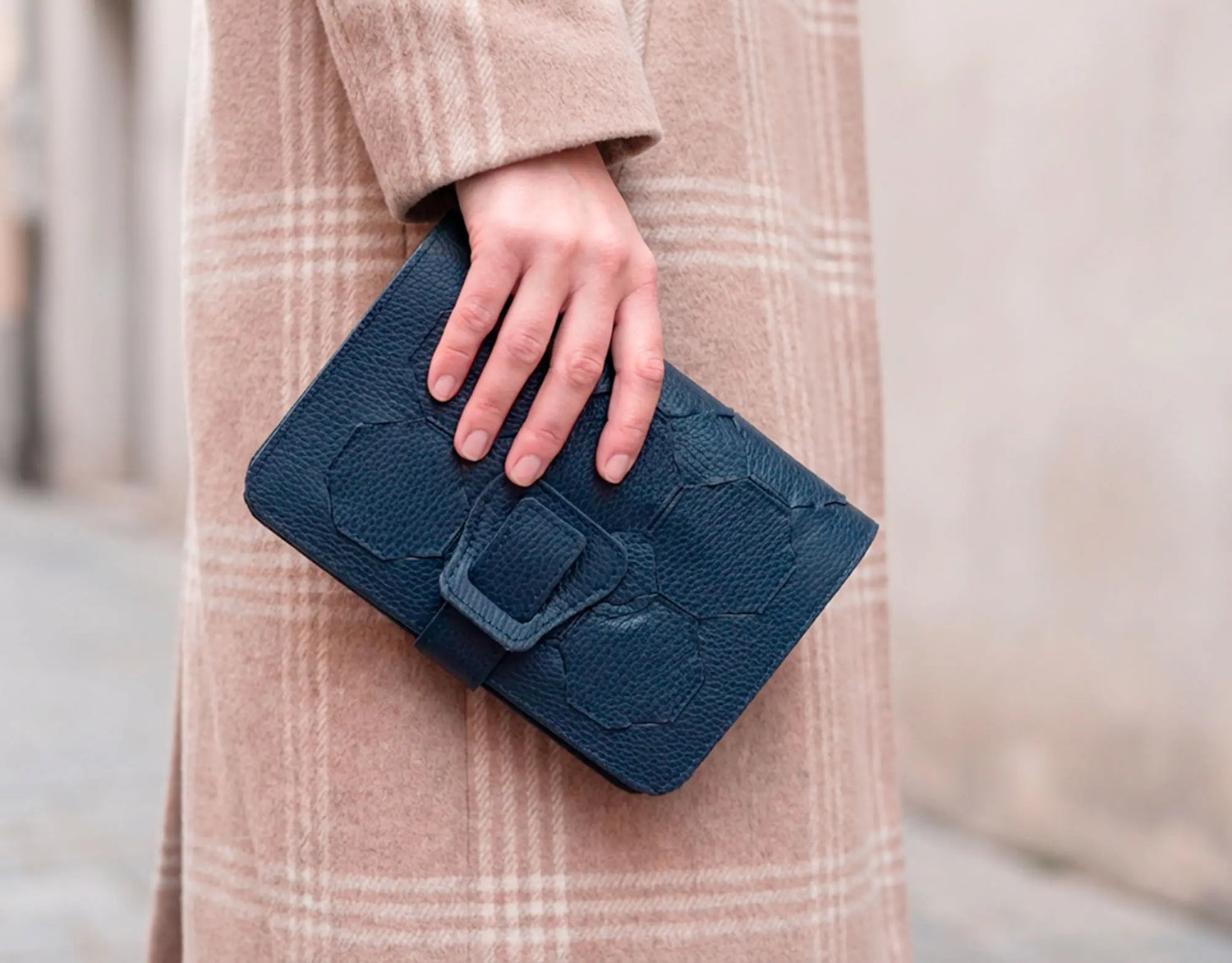Person holding a blue clutch bag with a blurred background