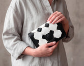 Person holding a black and white patterned clutch bag against a neutral background