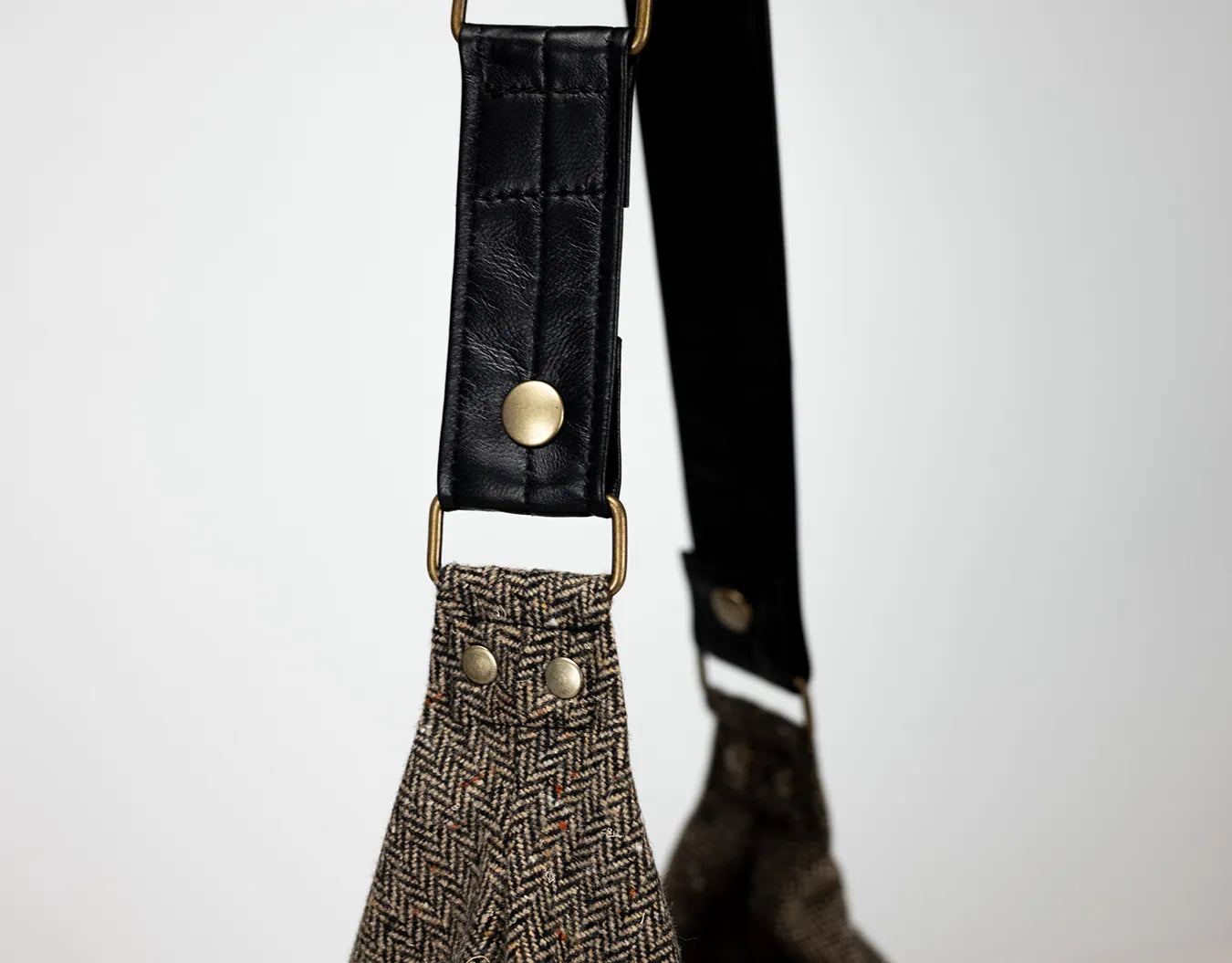 Black leather strap with gold hardware on a textured fabric background