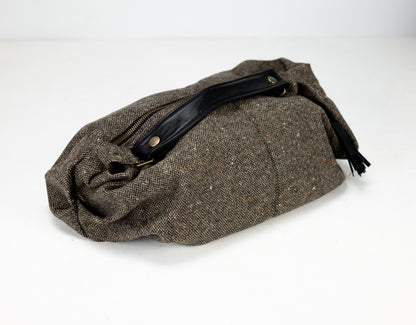 Brown woven bag with a black strap on a white background