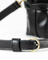 Close-up of a black leather belt with a gold buckle on a white background