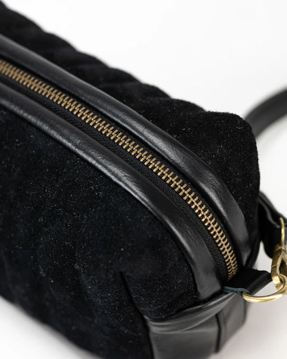 Black textured bag with gold zipper on a light gray background