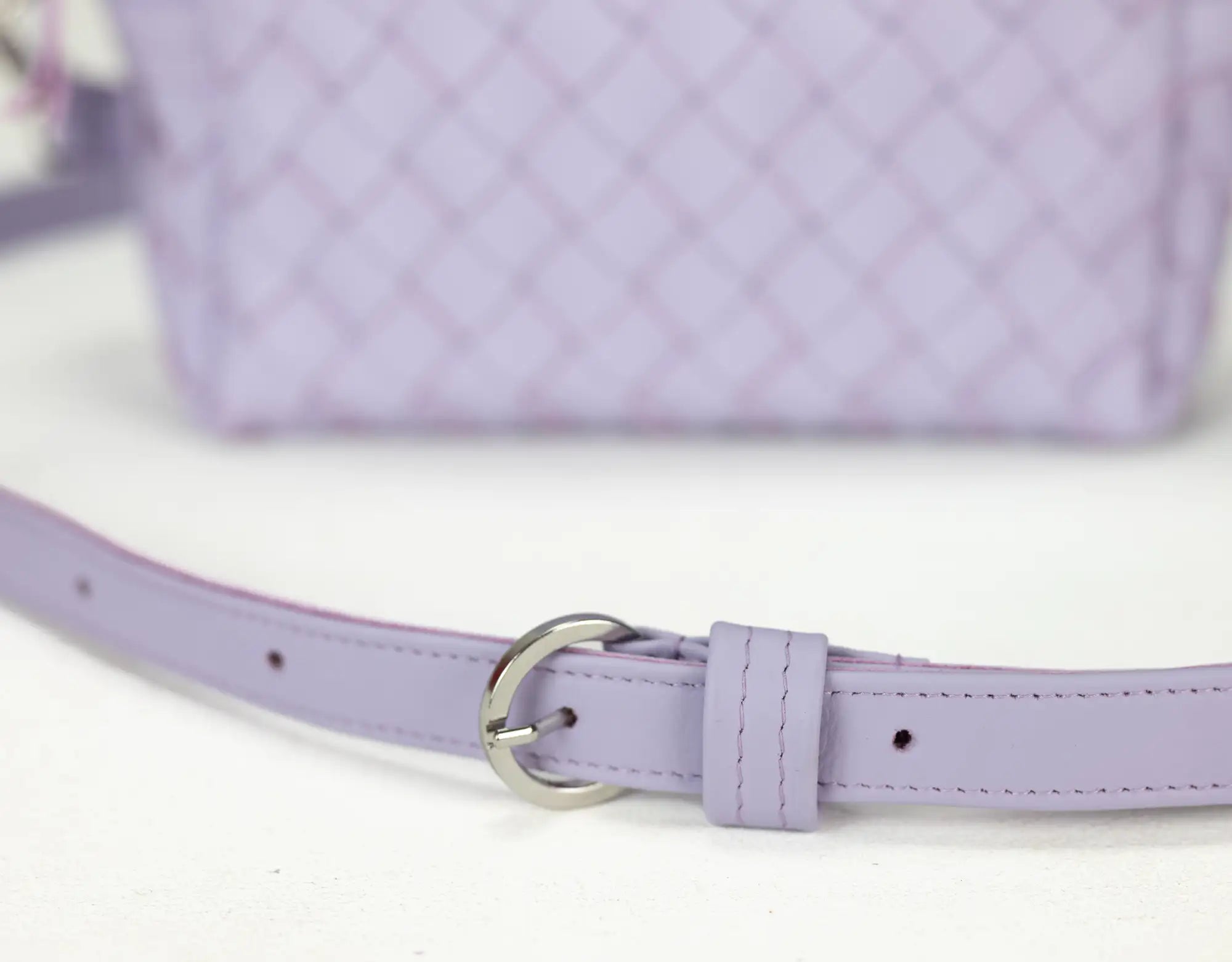 Close-up of a lilac handbag with a matching belt on a white background
